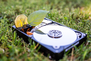 Hard disk drive with a bitcoin and a chia leaf on the grass