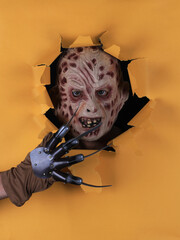 man in monster mask in yellow paper hole © serikbaib