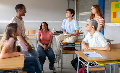 Group of multi-ethnic students talking in class during a break. High school, back to school, diverse students 