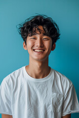 Asian man in white t-shirt smiling with confidence on blue background.