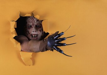 man in monster mask in yellow paper hole