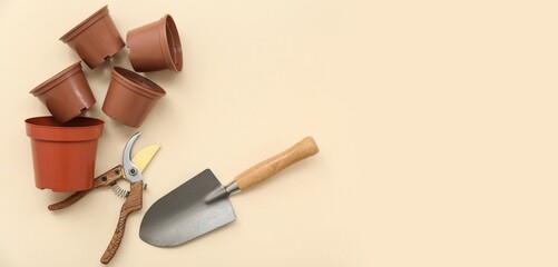 Pots, pruner and shovel on beige background with space for text
