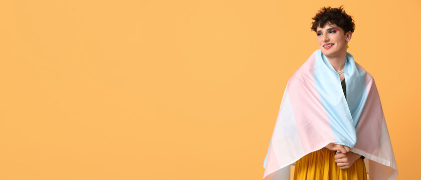 Young transgender woman with flag on yellow background with space for text