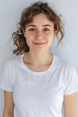 A woman in a white shirt poses for a photo, looking directly at the camera