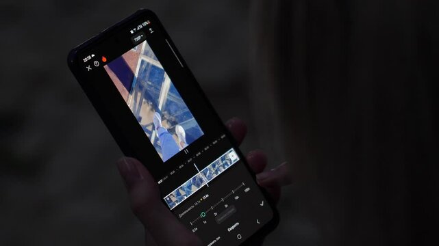 Video editor software on your phone. Woman editing video on her phone Crop content creator editing video on mobile phone while working on project.