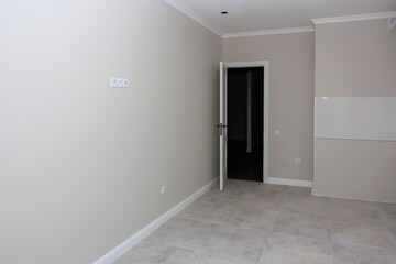 A white room with a door and a white board on the wall, typical apartment in a new building