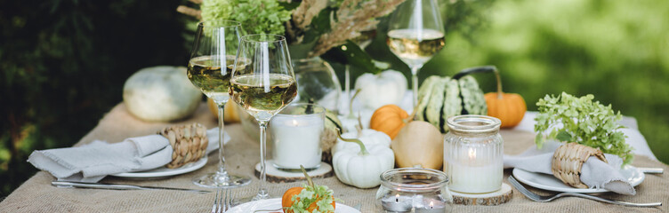 Fall still-life. Orange pumpkins, dry flowers and candles on linen tablecloth. Dinner table outdoors in the garden. Cozy autumn concept., simple handmade decoration, countryside style banner