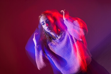 A young woman dances contemporary dances in blue and red light. Long exposure photo. 