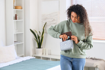 Young African-American woman putting asthma inhaler in bag at home