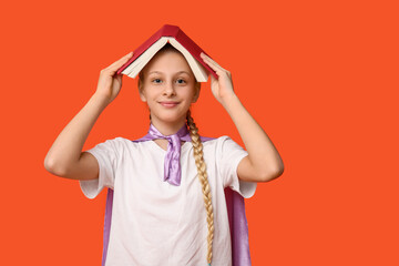 Cute teenage girl dressed as superhero with book on orange background. Library Lovers Day
