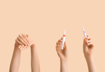 Female hands with cuticle oil pens on beige background