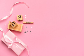 Cube calendar with date MARCH 8, gift box tied up with pink ribbon and confetti on pink background. International Women's Day. Top view