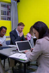 A group of people are sitting around a table, working on papers