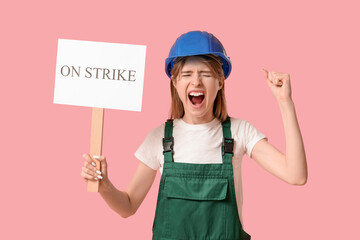 Protesting female construction worker holding placard with text ON STRIKE against pink background