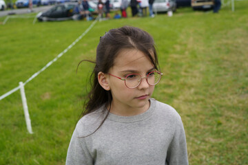 Little girl schoolgirl wearing glasses on a background of green grass. Children's travel concept