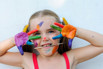 beautiful little girl artist in paints cheerful and funny mischievous