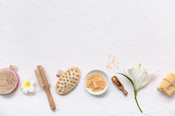 Sea salt, flowers, massage body brushes, spa stones and soap bars on white background
