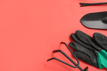Glove, gardening rake and shovel on red background