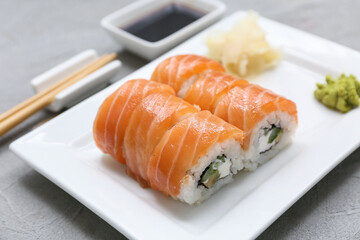 Plate with tasty sushi rolls, marinated ginger and wasabi on grey grunge background, closeup