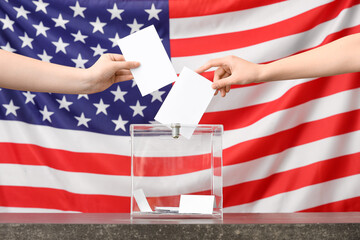 Voting women near ballot box on table against flag of USA