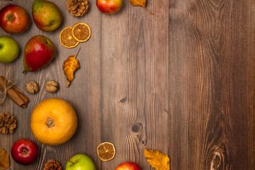 Autumn harvest. Pumpkin, pears, apples, nuts, pine cones, cinnamon and leaves on wooden background. Copy space, top view