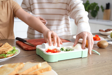 Mother with daughter cooking food for school lunchbox in kitchen, closeup