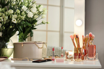 Decorative cosmetics and vase with flowers on table in dressing room