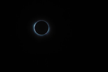 Total solar eclipse surrounded by the sun's crown and solar flares as the new moon comes between...