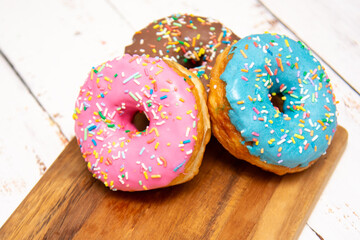 Delicious dessert. Pink, blue and chocolate donuts with multicolored sprinkles.