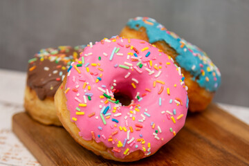 Delicious dessert. Pink, blue and chocolate donuts with multicolored sprinkles.