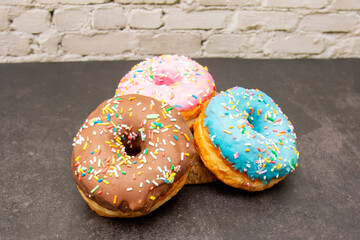 Delicious dessert. Pink, blue and chocolate donuts with multicolored sprinkles.