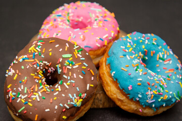 Delicious dessert. Pink, blue and chocolate donuts with multicolored sprinkles.