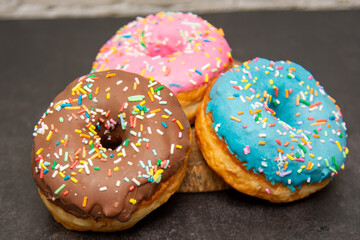 Delicious dessert. Pink, blue and chocolate donuts with multicolored sprinkles.