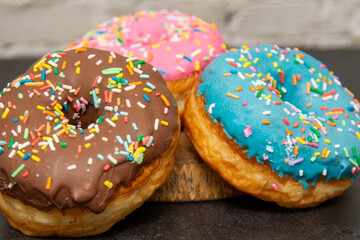 Delicious dessert. Pink, blue and chocolate donuts with multicolored sprinkles.