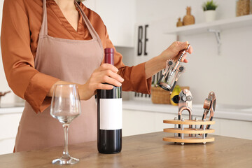 Woman with bottle of wine taking opener at home, closeup