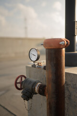 Water or gas pipeline with gate pressure valve installed on a concrete wall on the rooftop parking garage. Line pipe industrial and extinguisher, verticle
