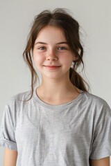 Obraz premium A close-up shot of a young girl with long brown hair wearing a gray t-shirt, suitable for editorial or commercial use