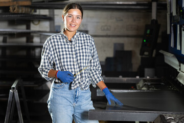 Portrait of positive female worker in workshop of a metallurgical plant