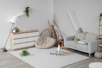 Interior of messy living room with overturned furniture and houseplant after earthquake