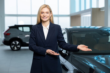 Blonde sale assistant showing a new car model