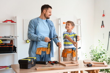 Happy father and his little son with different instruments assembling furniture at home