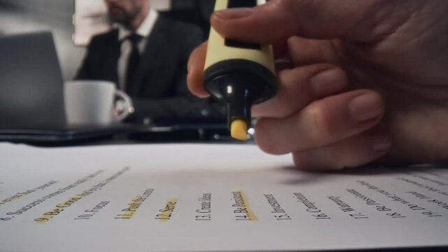 Extreme close-up shot of hand of unrecognizable businesswoman using yellow marker to highlight text on document in office