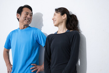 Upper half of a couple in their 50s doing sports, health, etc. Smiling, talking, conversing.