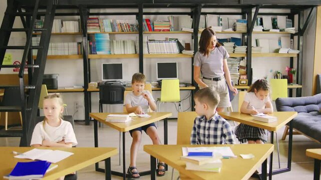 A teacher is providing help and guidance to young students in a classroom, creating an engaging academic environment for learning and development