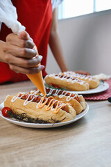 Hand Adding Cheese and Mustard Sauce into Hotdogs. Hotdogs Topped With Mayonnaise And Cheese. Small...