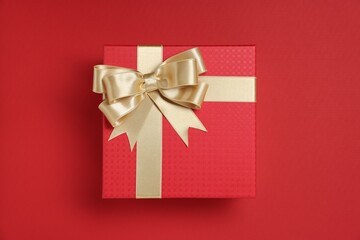 Gift box with bow on red background, top view