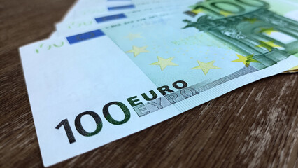 Close up photo of 100 euro. The front side of a 100 euro banknote on wooden table.