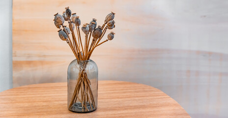 Dried poppy flowers. Bouquet of dried flowers in a glass vase on a wooden table. Copy space