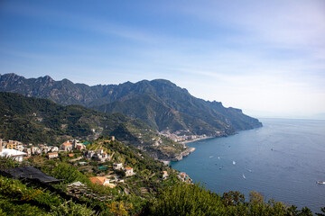 A Stunning view of the Amalfi Coast, seen from the Mountain town of Ravello mid day. Greenery explodes on the hillsides contrasting the stark white buildings which look down on the many boats in the