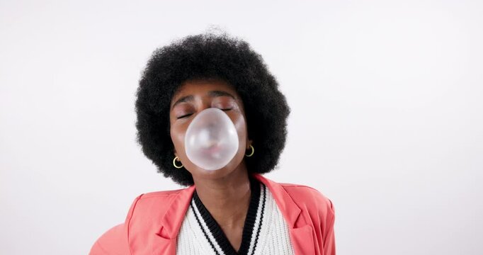 Black woman, blowing and pop with bubblegum in fashion for silly or goofy trick on white studio background. Portrait of young African, female person or model with afro, humor and playing with candy